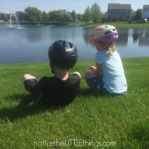 siblings sitting by a pond